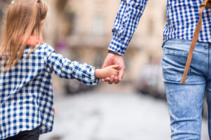 Hands of man and child holding together on street at european city